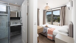 A modern hotel room with a bathroom, a bed, a desk, and a view of the outside. - Villa Lidya in Dalyan (Ortaca)
