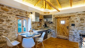 A rustic kitchen with stone walls, wooden beams, and a large wooden door. - Villa Liana in Spartia (Messini)