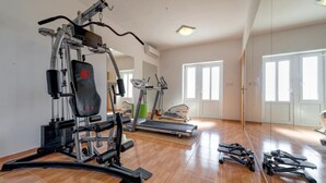 Et hjemmegymnasium med bænkpresser, crosstrainer og løbebånd.