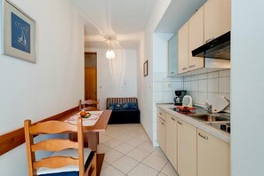 Eine kompakte Küche mit Essbereich, einer Couch und einem kleinen Tisch.