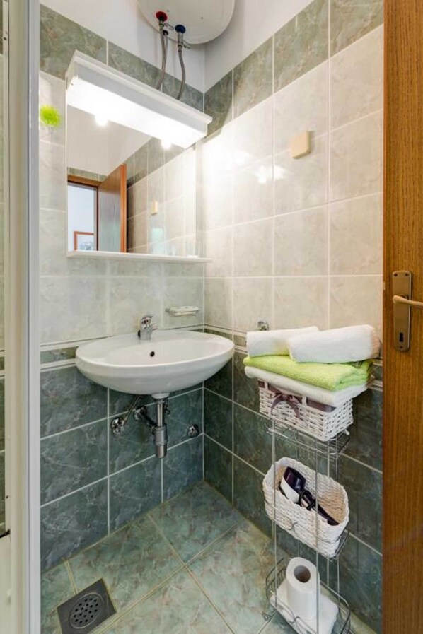 A bathroom with a white sink, a mirror, and a towel rack with folded towels.