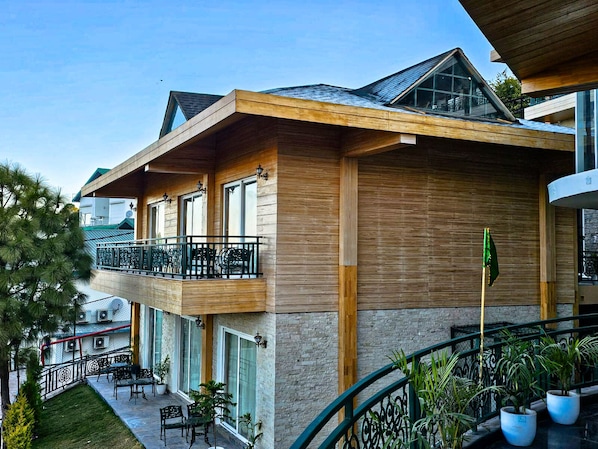 A modern building with a wooden facade, a balcony with outdoor seating, and a flag.