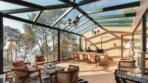 A spacious room with a glass ceiling, wooden furniture, and a view of trees. - Royalpine Rosastays Kasauli (Kasauli)