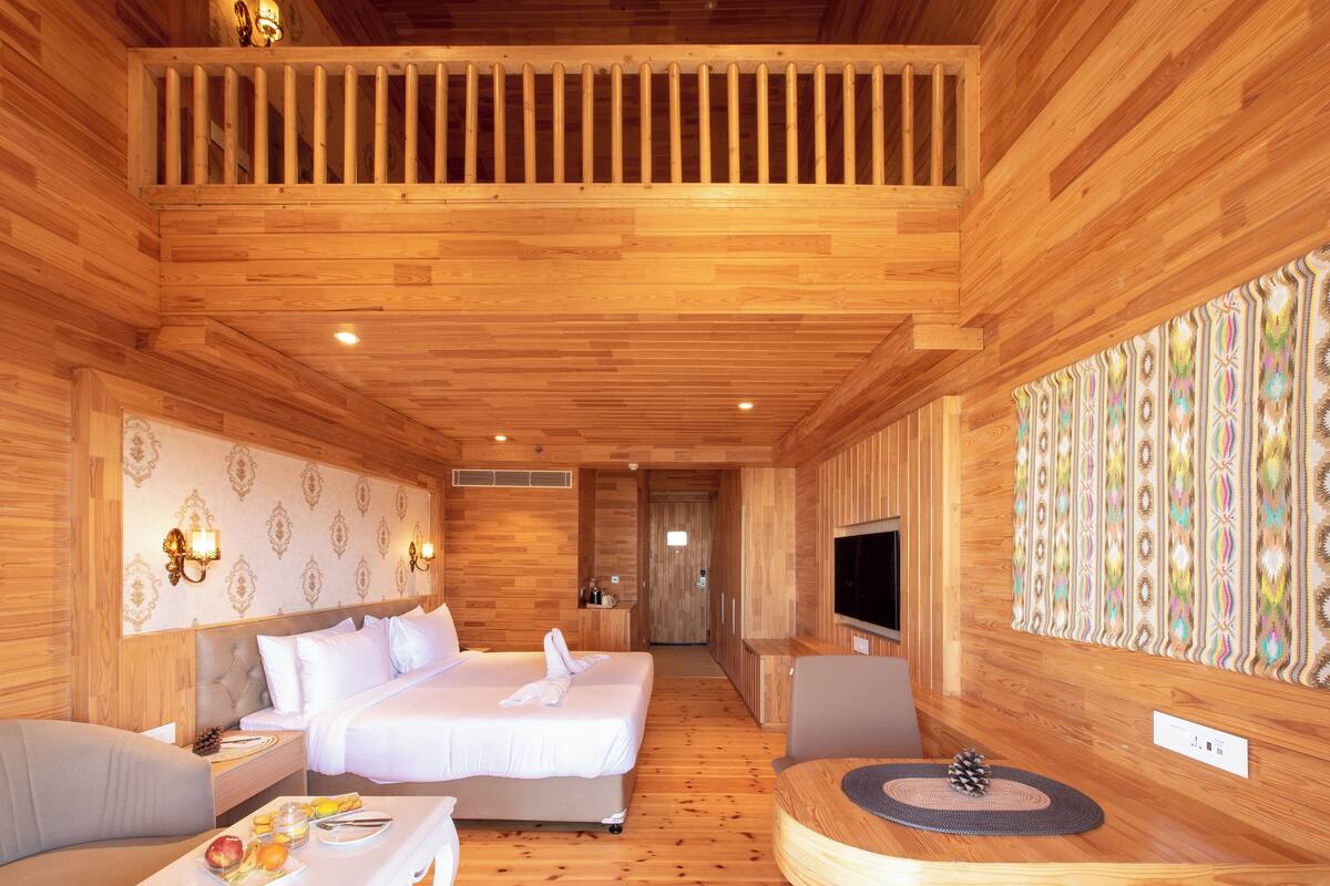 Ein Schlafzimmer mit Holzboden, einem Bett, einem Nachttisch und einem Fernseher an der Wand.