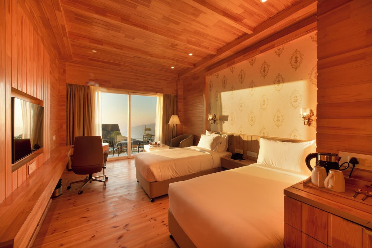 Ein Zimmer mit Holzwänden, zwei Betten, einem Schreibtisch, einem Stuhl und einem großen Fenster.