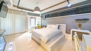 Ein modernes Schlafzimmer mit einem großen Bett, Nachttischen, einem Schreibtisch und einem Sessel.