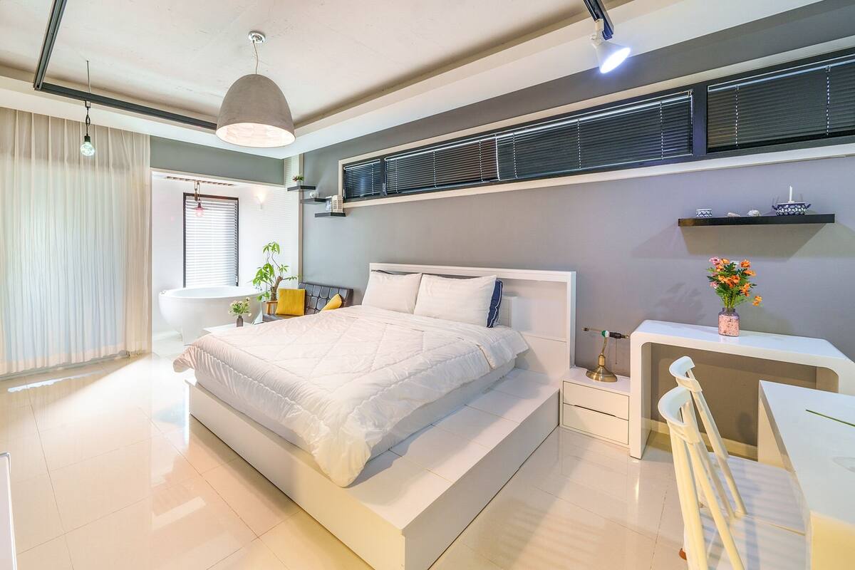A modern bedroom with a large bed, bedside tables, a desk, and a chair.