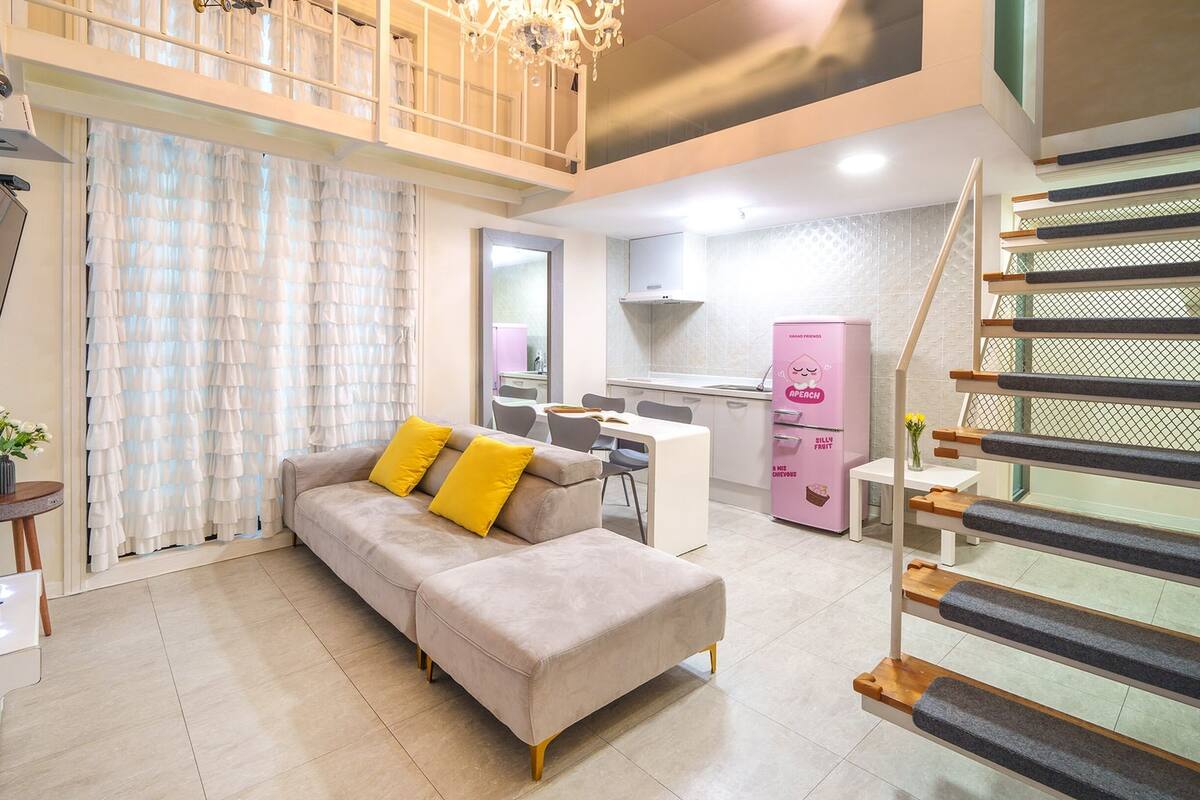 A modern living room with a sofa, a dining area, and a kitchen.