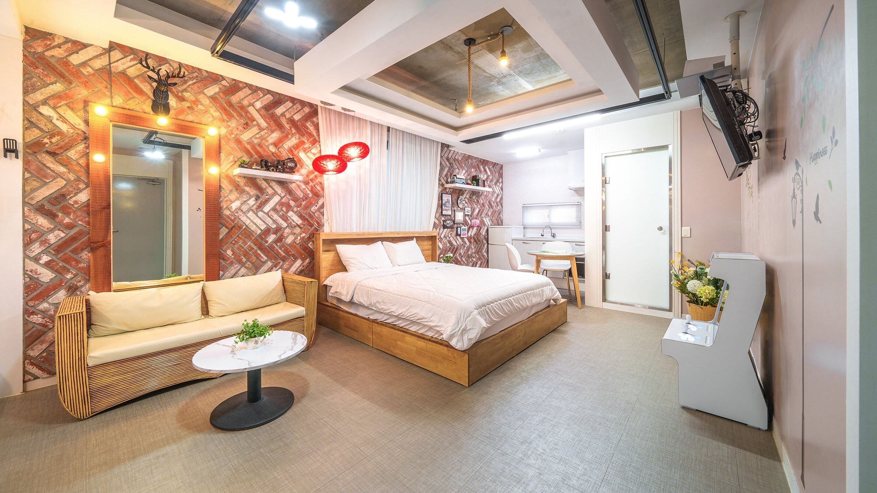 Een moderne hotelkamer met een groot bed, een bank, een kleine tafel en een kitchenette.