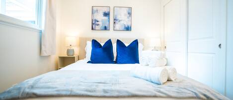 A hotel room with a bed, two bedside tables, a window, and two abstract paintings on the wall.