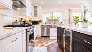 Una cocina moderna con armarios blancos, electrodomésticos de acero inoxidable y suelo de madera.