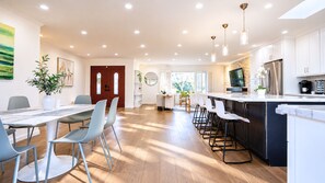 Una cocina moderna con una isla central, taburetes de bar y un comedor con sillas.