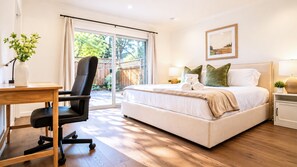 Un dormitorio con cama, mesitas de noche, escritorio y silla.