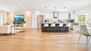 A modern kitchen with white cabinets, a stainless steel refrigerator, and a bar area with stools.