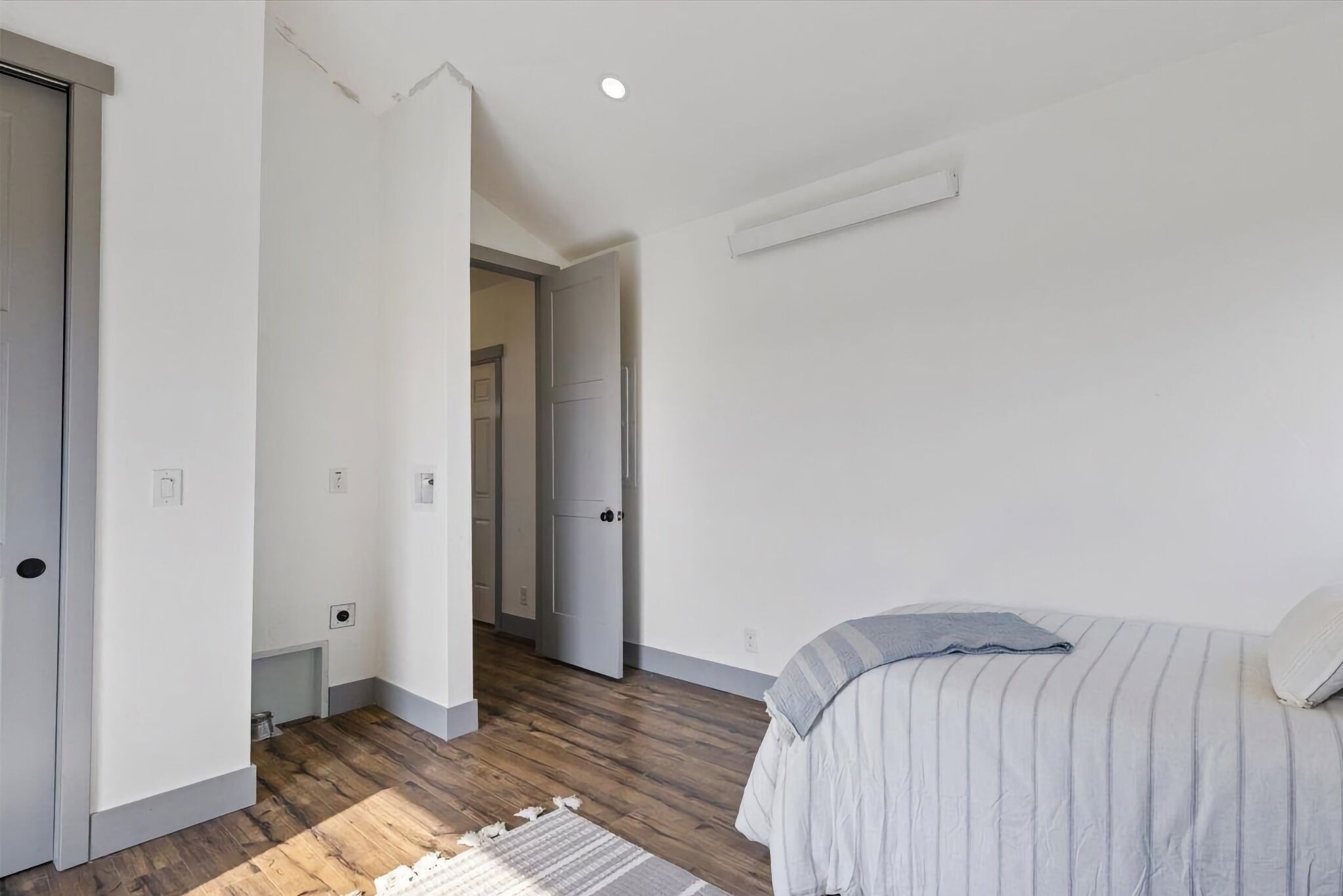 Une chambre à coucher avec un lit, une porte et un couloir.