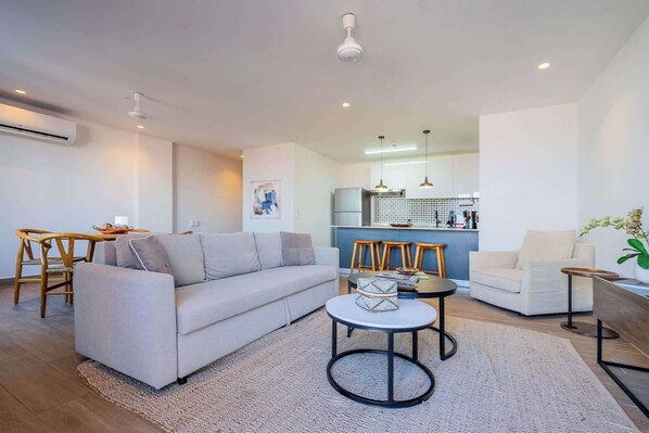 Una sala de estar moderna con un sofá, una mesa de comedor y una cocina al fondo.