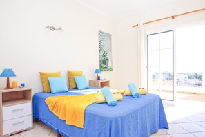 A bedroom with a bed, two bedside tables, a nightstand, a window, and a view of the outside. - Villa Bella Vista (Albufeira)