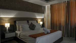 A hotel room with a large bed, two bedside tables with lamps, a headboard, and a view of curtains. - Princess Keisha By SECOM (Denpasar)
