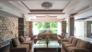 A spacious living room with a large window, a stone wall, and a modern chandelier. - Princess Keisha By SECOM (Denpasar)