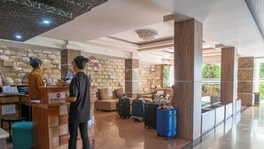 A reception area with a check-in counter, a seating area with a sofa and chairs, and a luggage storage space. - Princess Keisha By SECOM (Denpasar)
