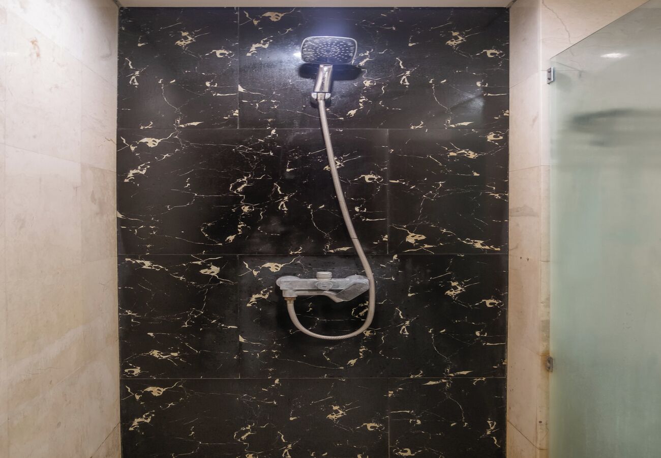 A shower with a handheld showerhead and a handheld shower attachment.