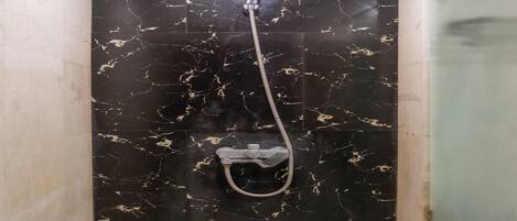 A shower with a handheld showerhead and a handheld shower attachment.