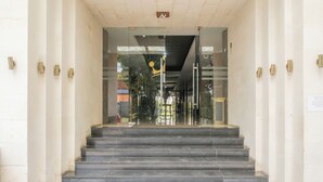 A set of marble stairs leading to a glass door entrance with a metal railing. - Princess Keisha By SECOM (Denpasar)