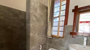 Une salle de bain comprenant des toilettes, un lavabo et un espace douche.