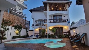 Un bâtiment à deux étages doté d’une piscine, d’un espace extérieur aménagé et d’un balcon.