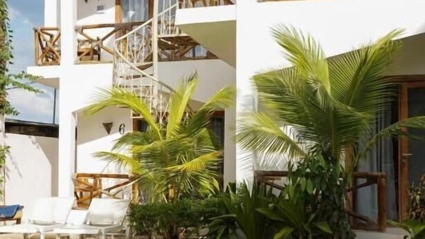 Un hôtel doté d’une piscine, de palmiers et d’un escalier menant aux étages supérieurs.