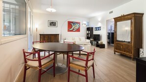 A dining area with a round table and chairs, a white sofa, and a wooden cabinet.