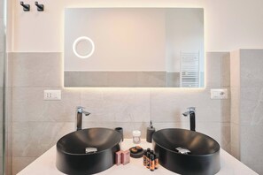A modern bathroom with two black sinks, a large mirror, and a towel rack.
