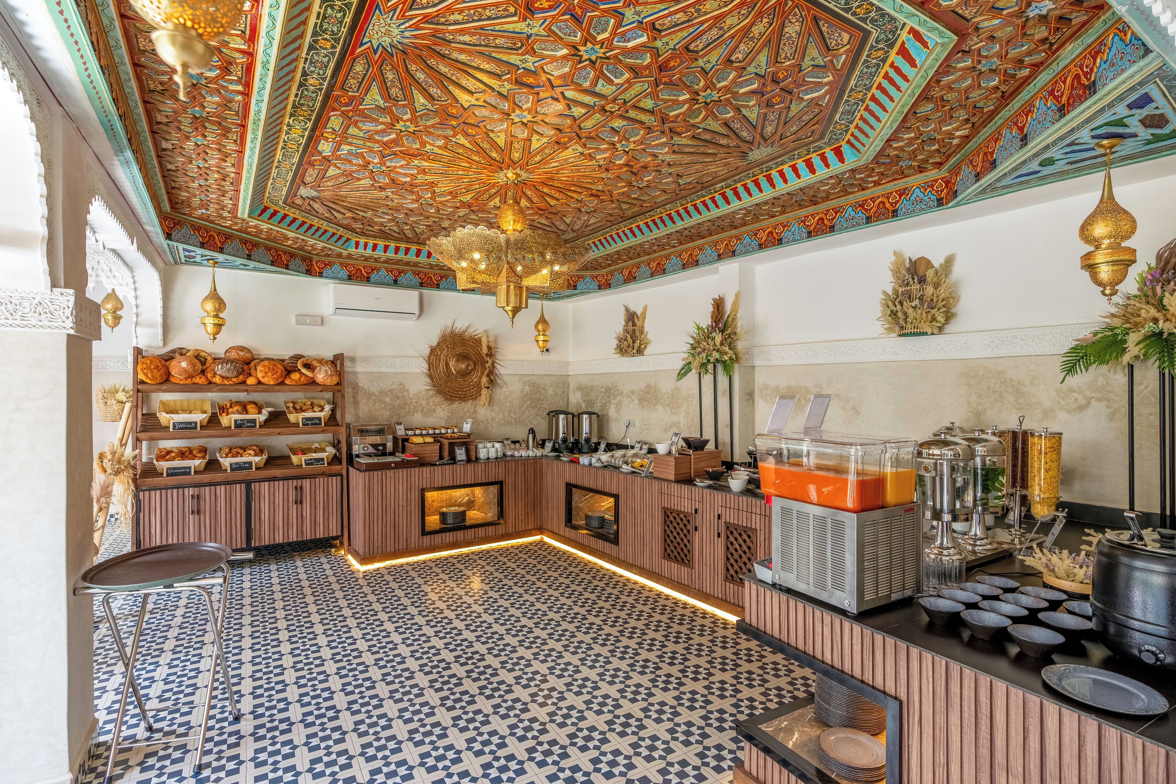 A breakfast bar with a patterned tile floor, a decorative ceiling, and various food items and beverages.