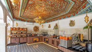 A breakfast bar with a patterned tile floor, a decorative ceiling, and various food items and beverages.