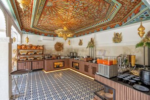 A breakfast bar with a patterned tile floor, a decorative ceiling, and various food items and beverages.