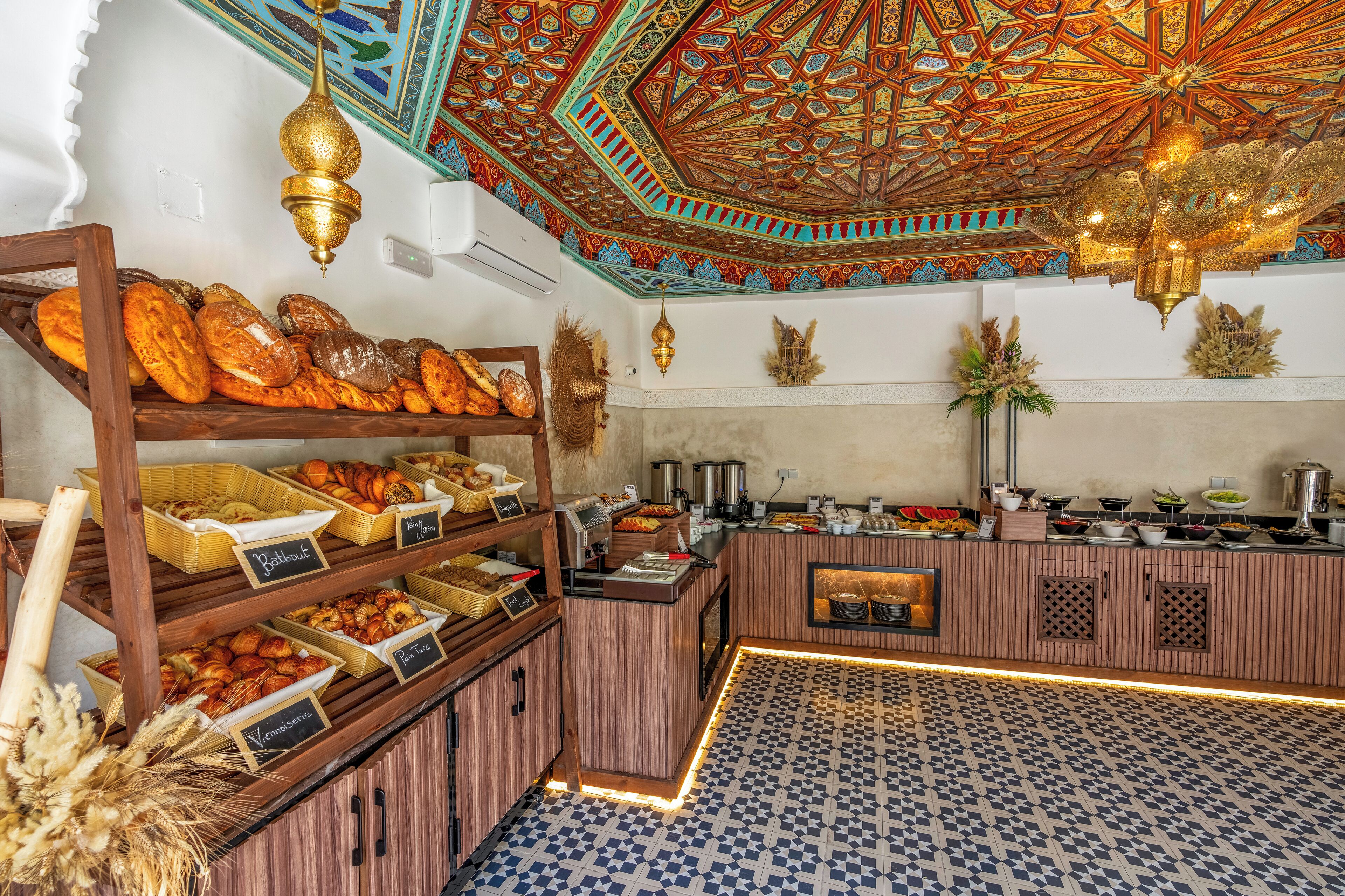 A breakfast buffet with various baked goods and a decorative ceiling.