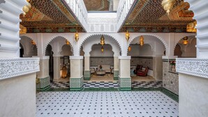 An interior with a checkered floor, ornate arches, and a central seating area.
