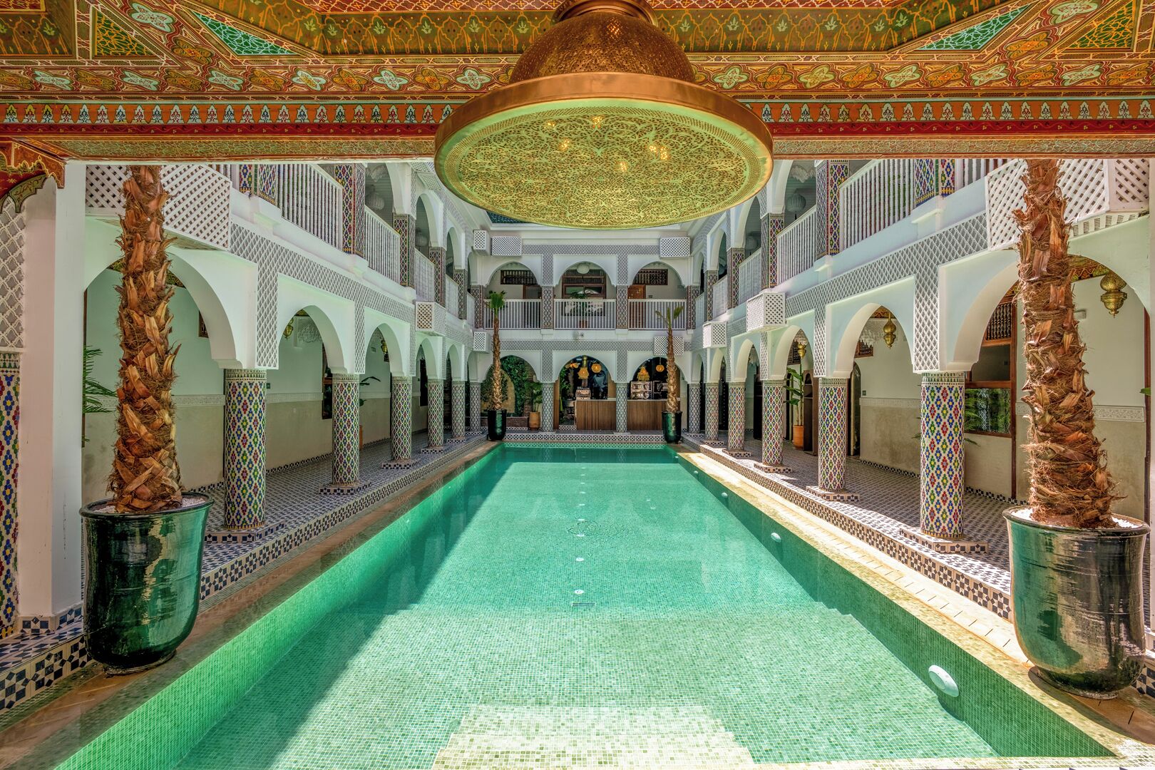 Una piscina interior lujosa con paredes de azulejos ornamentados y un techo alto con diseños intrincados.