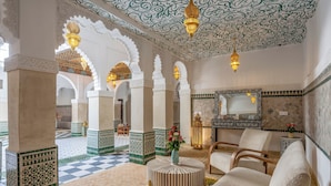 A traditional interior with ornate arches, a checkered floor, and a seating area with a round table and chairs. - Palais Moulay Said & SPA (Marrakech)