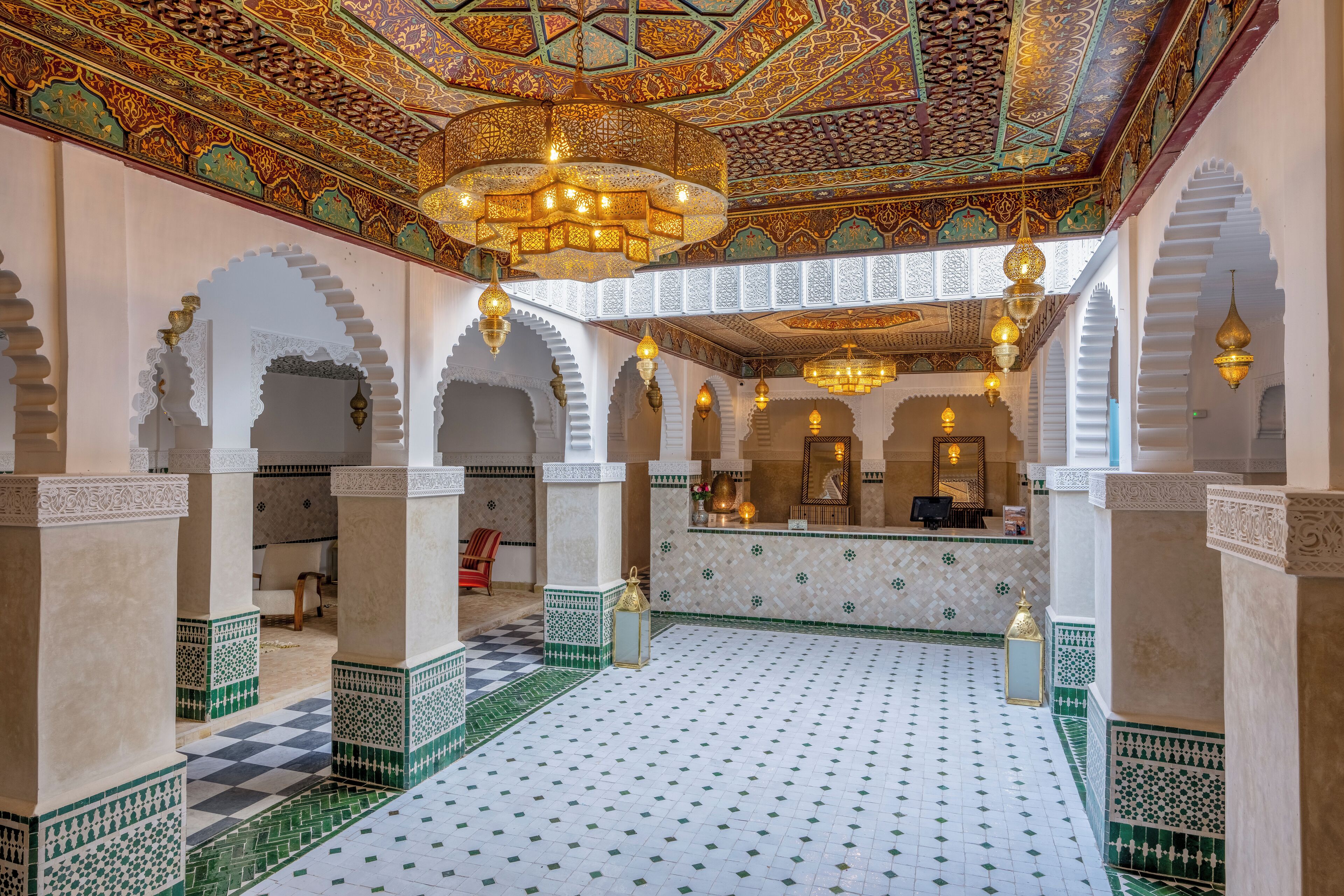 An interior with ornate ceiling, arches, and patterned floor tiles.