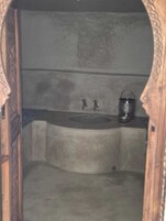Un baño pequeño y cerrado con un lavamanos y un recipiente de metal.