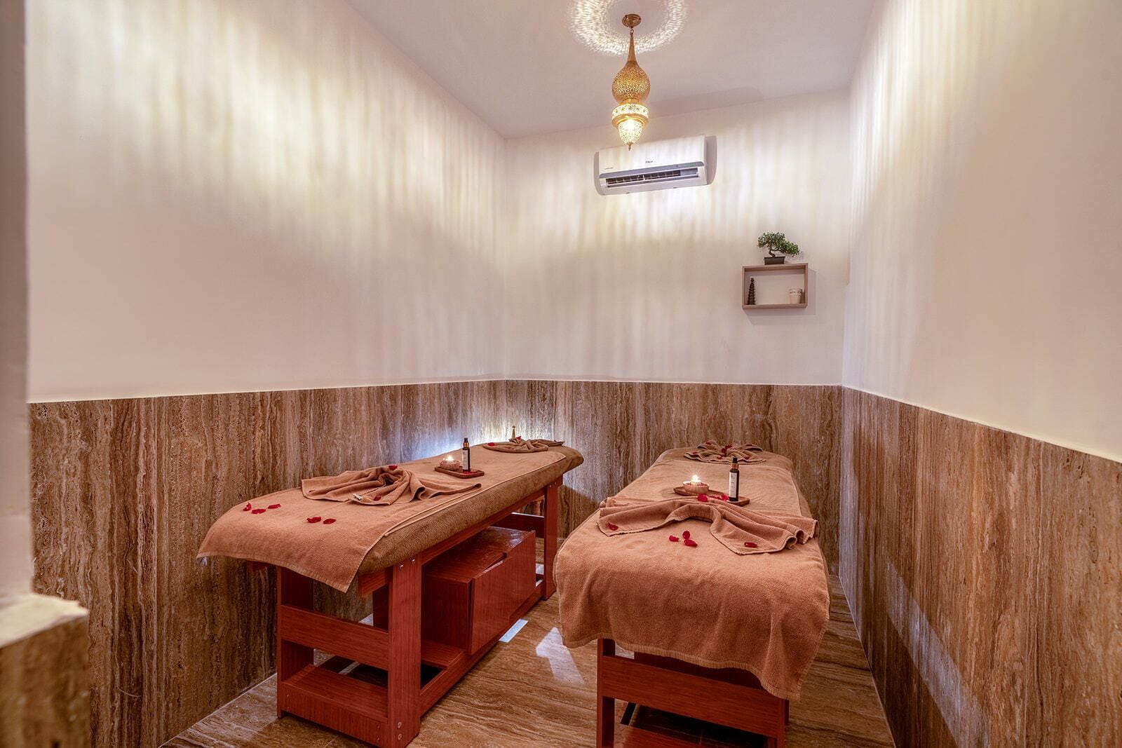 A spa room with two massage tables, each covered with a towel and a bottle of oil.