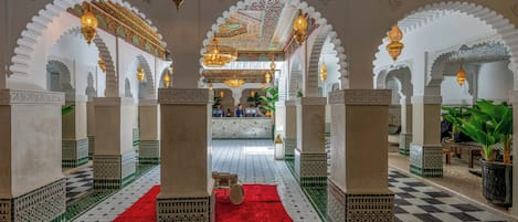An interior with arches, patterned flooring, and hanging lamps.