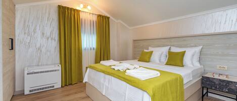 Una habitación de hotel con cama, mesita de noche, aire acondicionado instalado en la pared y una ventana con cortinas.