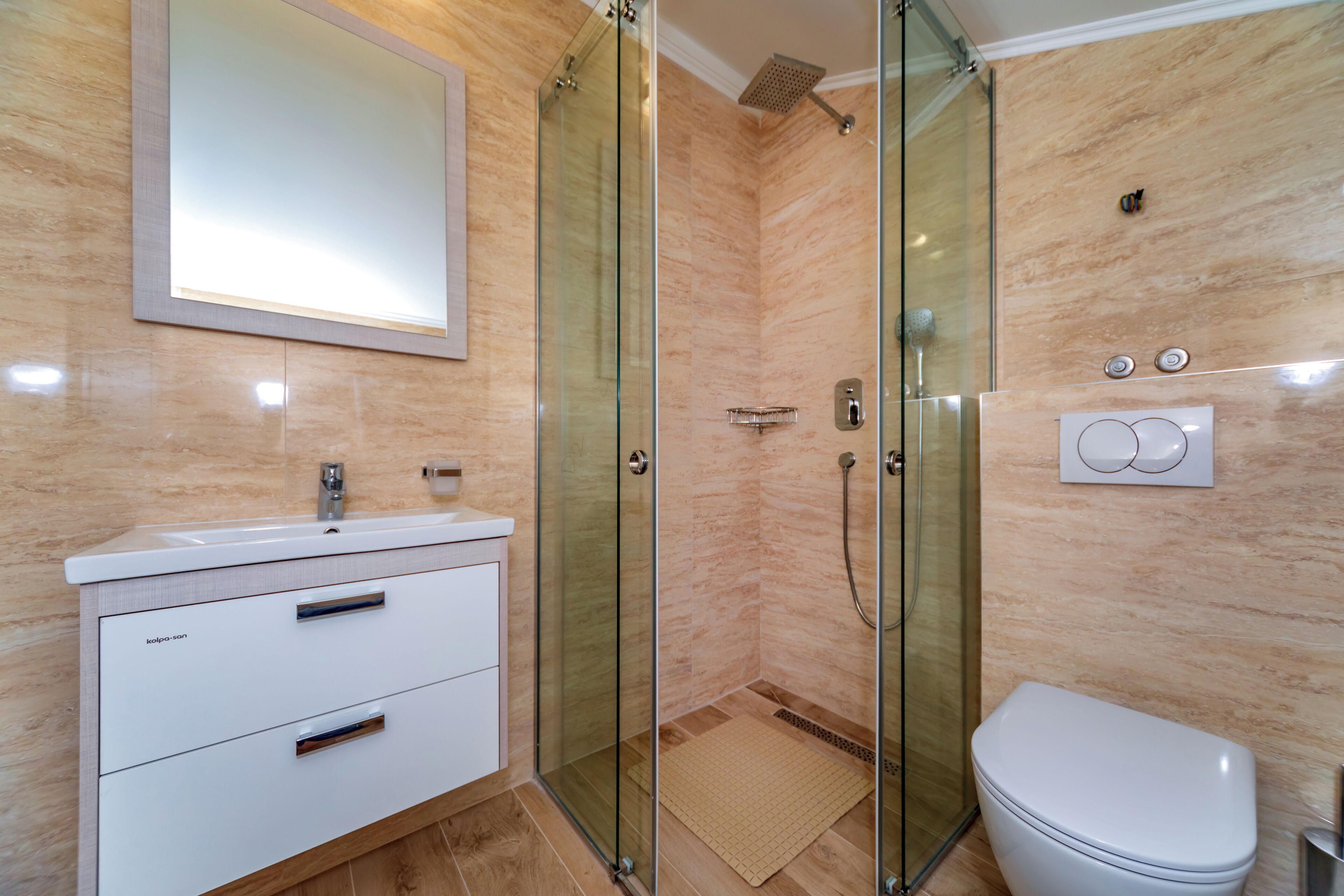 A modern bathroom with a glass-enclosed shower, a white sink, and a toilet.