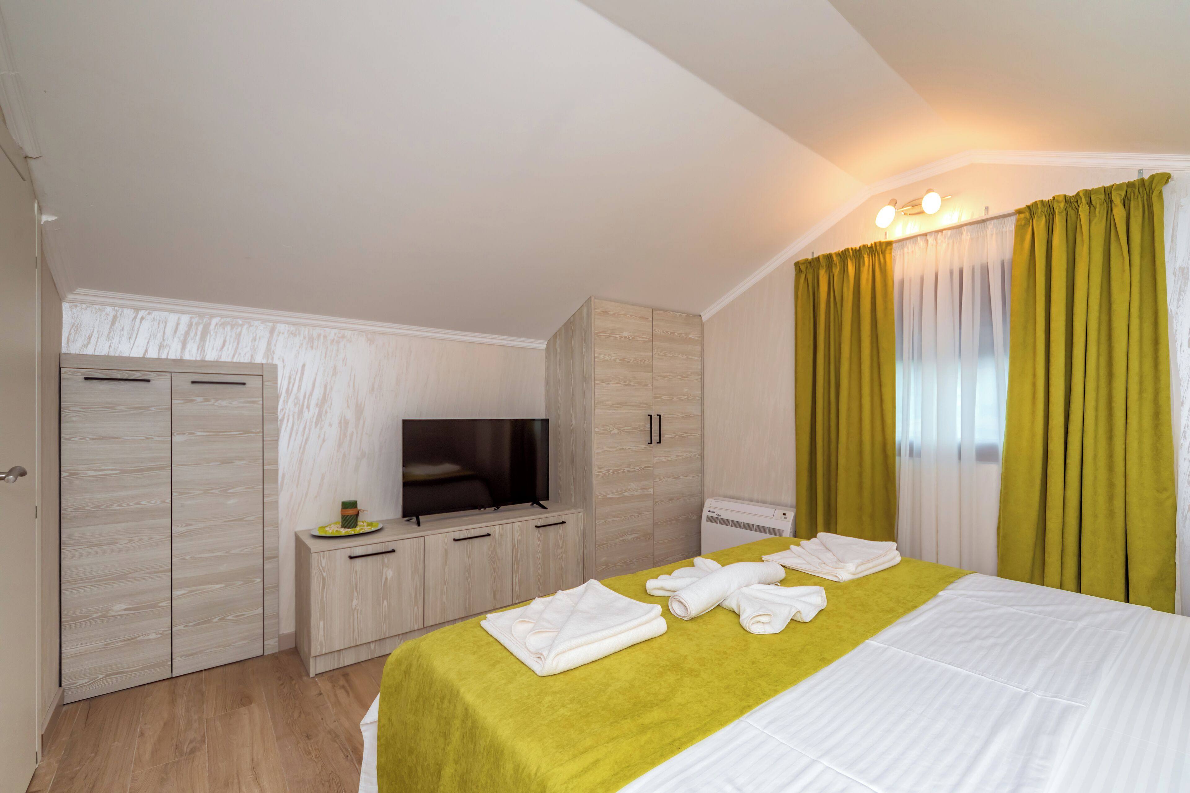 A hotel room with a bed, a television, a wardrobe, and a bathroom.
