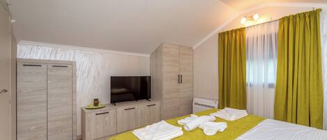 Una habitación de hotel con cama, televisión, armario y baño.