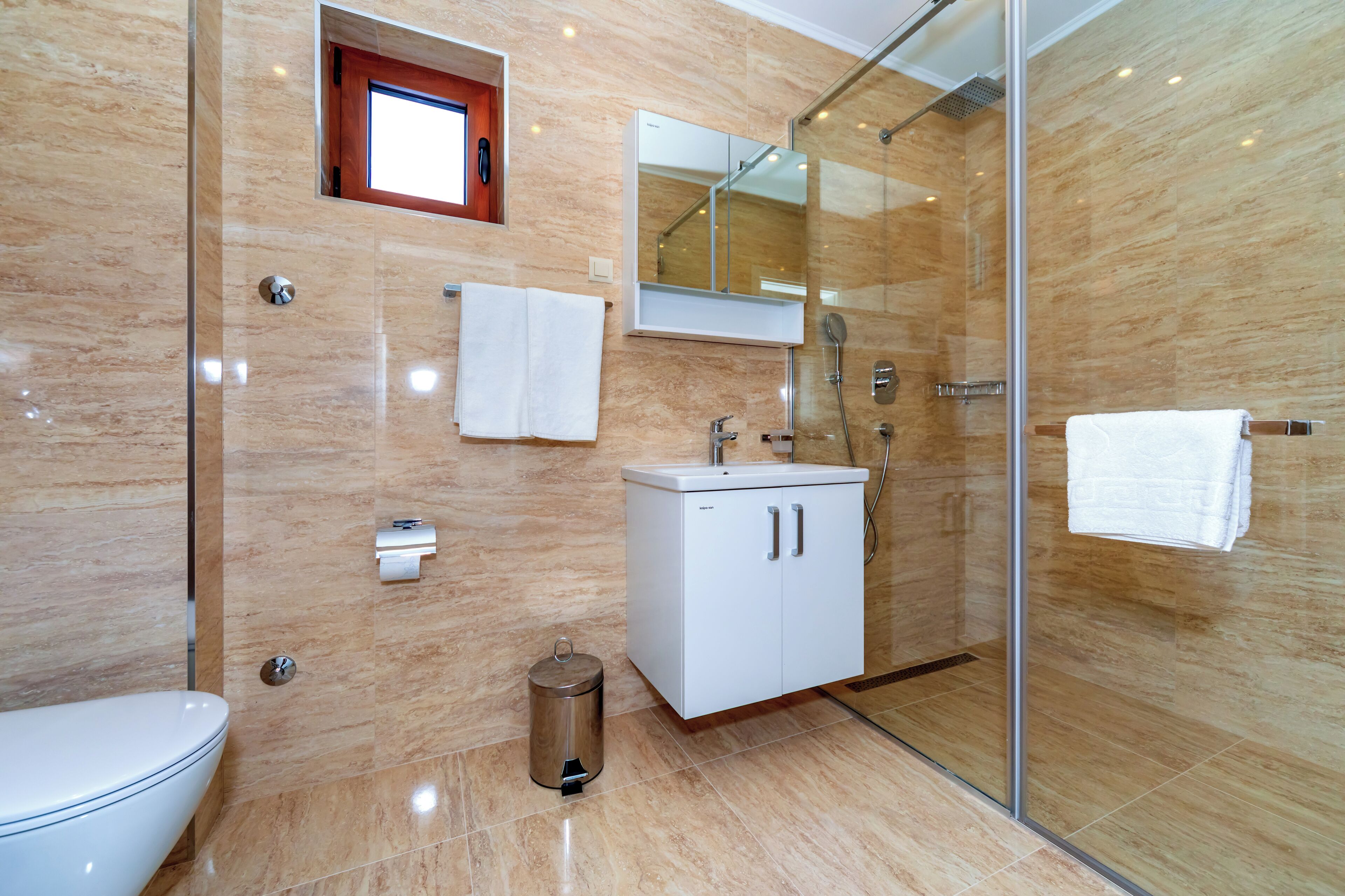 Un bagno moderno con box doccia in vetro, lavandino bianco e water.