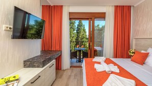 Una habitación de hotel con cama, televisión, escritorio y balcón con mesa y sillas.