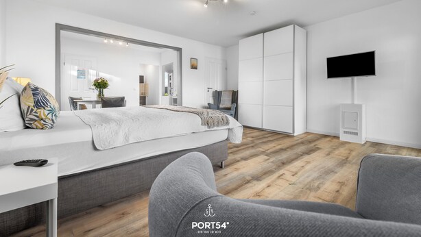 Une chambre d’hôtel moderne équipée d’un grand lit, d’un bureau, d’une télévision et d’une armoire.